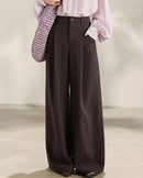 Women's light brown high-waist pleated wide-leg trousers, featuring a fluid polyester-viscose blend and back elastic waist for polished comfort from morning commute to evening dinner.