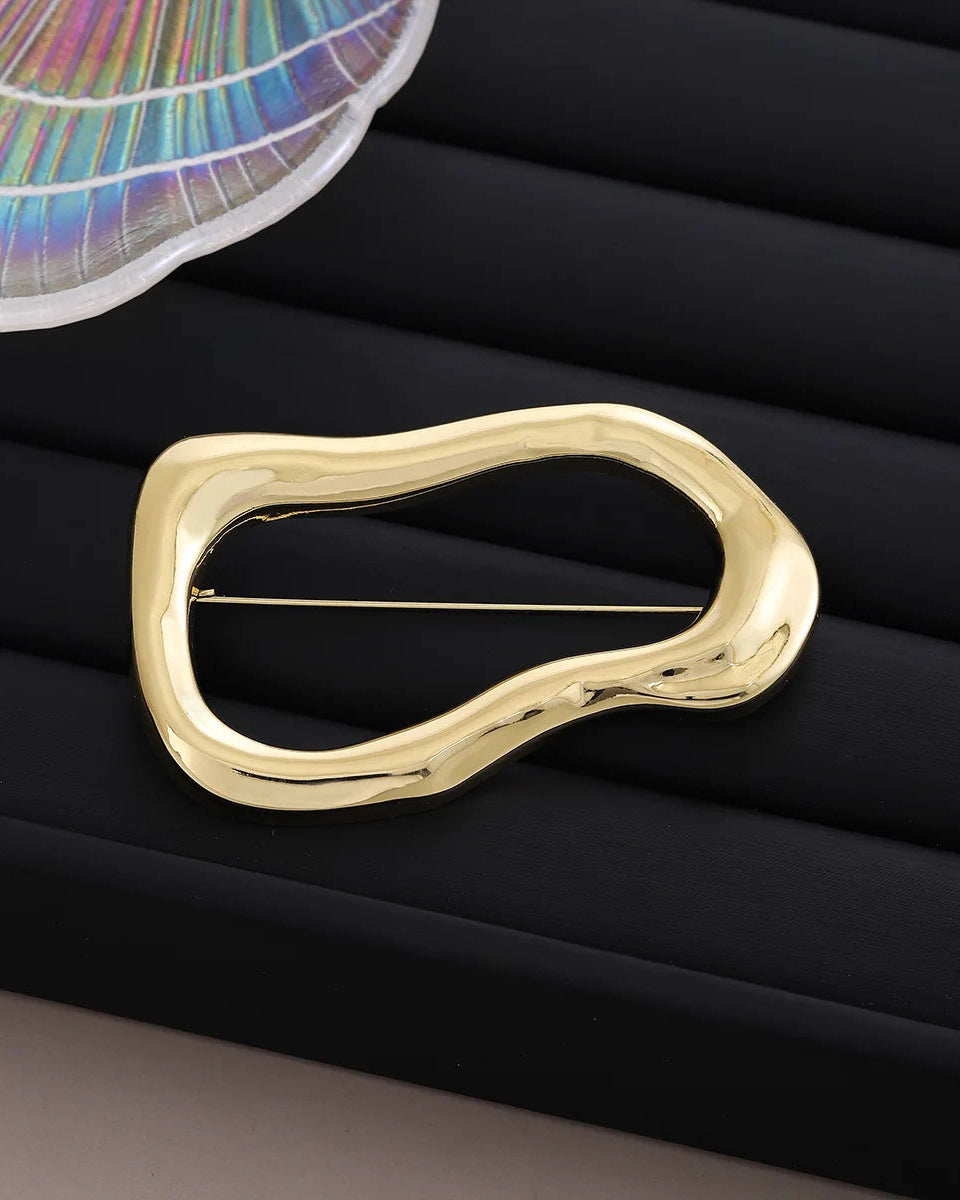Irregular oval polished brooch in gold tone, smooth curved metal pin with a modern organic shape, perfect for minimalist elegance.