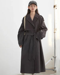 A cotton-Lyocell blend trench coat with a turn-down collar, single-breasted front and waist tie, designed for polished ease that layers from commute to weekend.