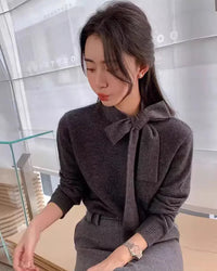 A soft cashmere tie-neck sweater for women featuring an adjustable bow detail at the neck, a relaxed fit, and long sleeves for easy fall and winter layering.