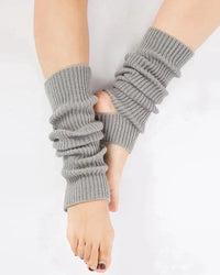 A pair of loose knit dance leg warmers with a slouchy mid-length fit, designed for stretchy comfort that layers easily over leggings for studio or gym.