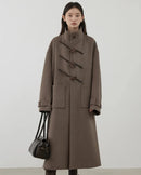 A 50% wool blend long coat with a high stand collar, horn buttons and drop shoulders, designed for polished warmth that layers from commute to weekend.
