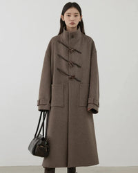 A 50% wool blend long coat with a high stand collar, horn buttons and drop shoulders, designed for polished warmth that layers from commute to weekend.