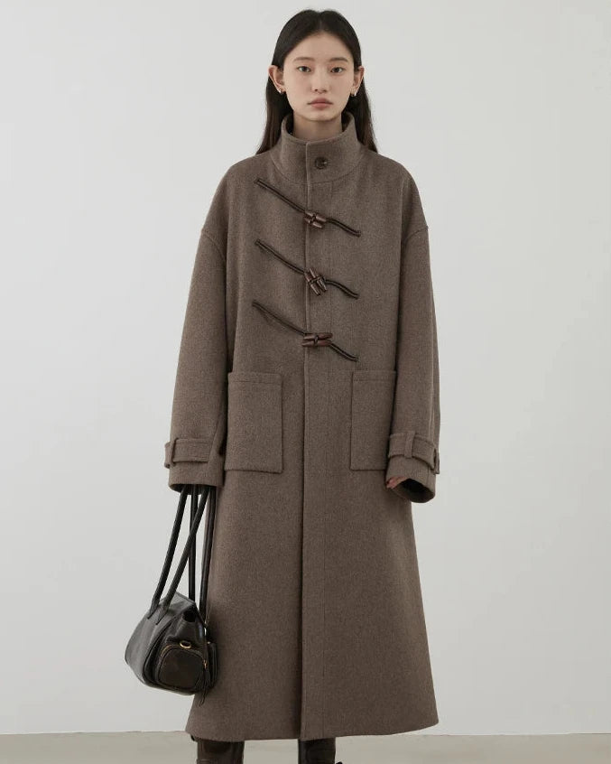 A 50% wool blend long coat with a high stand collar, horn buttons and drop shoulders, designed for polished warmth that layers from commute to weekend.