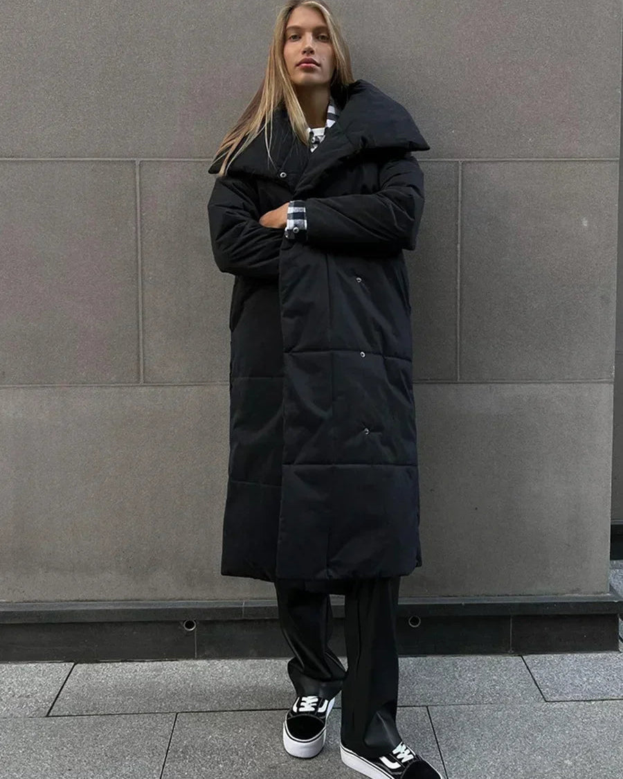 Broad quilting gives the surface a clean, understated rhythm, complemented by a statement collar and matching belt.