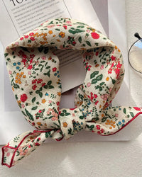 A small square scarf with a fine floral print and light smooth fabric, designed to knot at the neck, tie as a headband, or accent a bag.