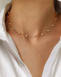 A vintage-inspired choker necklace featuring lustrous glass pearl beads on a delicate gold-tone chain, secured with a lobster clasp for a timeless look.