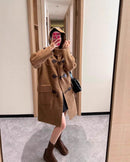 Woman braving snowy campus in camel sheep-wool duffle coat, oversized hood and wooden toggles lock in warmth for winter walks .