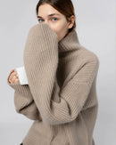 Woman brunching in a Turtleneck Loose-Fit Cashmere Sweater, 19-micron Mongolian fibers and relaxed drop-shoulders give cloud-soft warmth—your luxe yet breathable 55-70 °F cold-season essential.