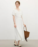 Woman posing in a pastel V-neck dress with textured puff sleeves, soft woven crepe drapes into a flattering midi length—perfect for spring brunches or daytime weddings.