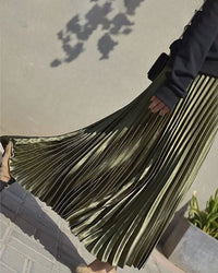 Woman twirling in a velvet high-waist pleated skirt, rich emerald pile catches the light while the 32-inch midi hem skims boots—your luxe statement for 50-70 °F fall-through-spring dinners.