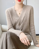 Women’s merino-wool V-neck pullover with cross-twisted front and relaxed long sleeves—sculptural layer for office days, weekend cafés or gallery openings.